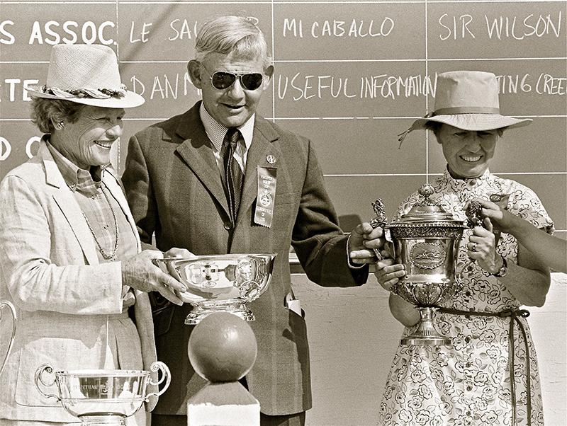 man and 2 women with trophies
