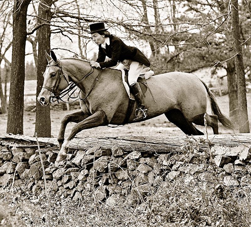 foxhunter in formal attire jumping stone fence