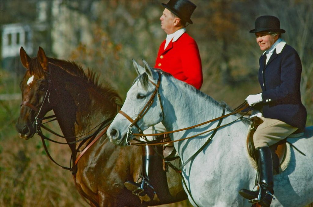 Man and woman in formal hunt attire riding horses