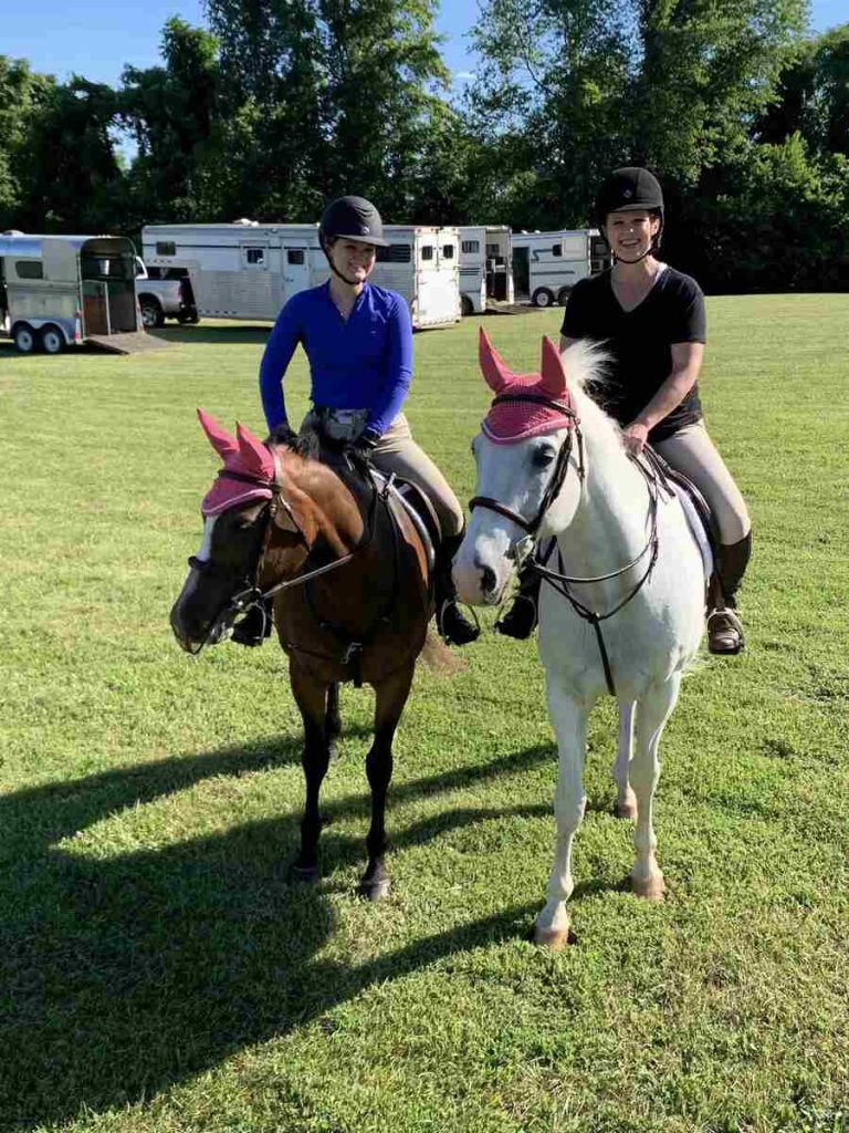 two women on horses with pink ear bonnets