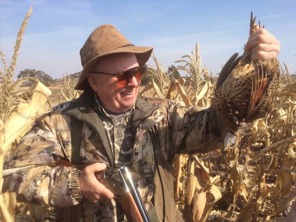 Man holding rifle and dead bird