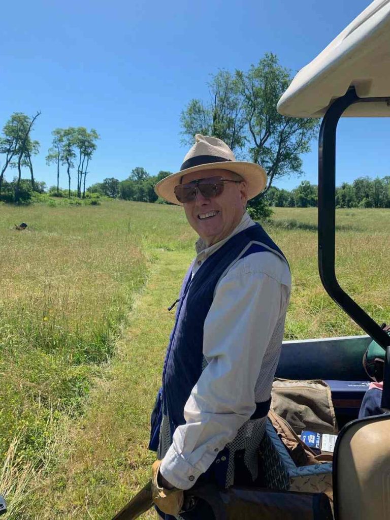 Man with hat standing next to golf cart