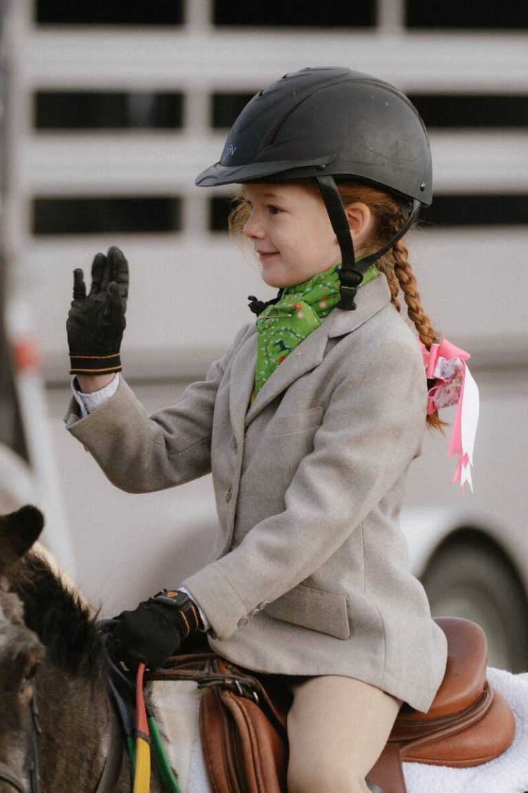 Small girl in hunt attire with hand raised